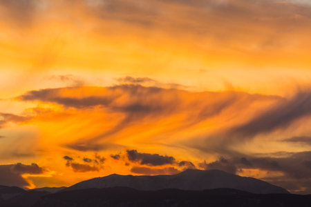 amazing colorful clouds with storm during sundown in a flat landscape with a moutainの写真素材