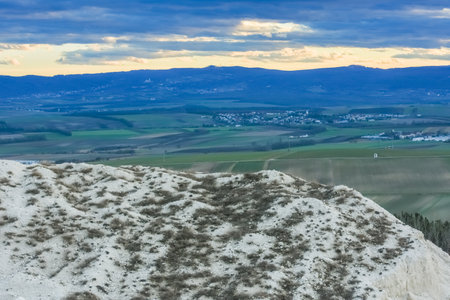 hill from a lime quarry with shrubs and a landsape with fields and housesの写真素材