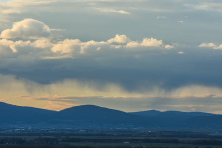 rain under clouds over a landscape with mountains in the springの写真素材