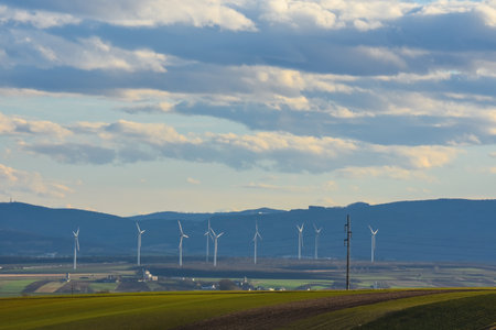 lot of windmills in a landscape with fields forest and houses with clouds at the skyの写真素材