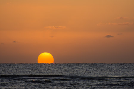 amazing sunrise with a distorted orange sun at the horizon from the red sea in egyptの写真素材
