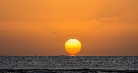 magicl sunrise with a burning and torn orange sun at the horizon from the red sea in egypt panorama viewの写真素材
