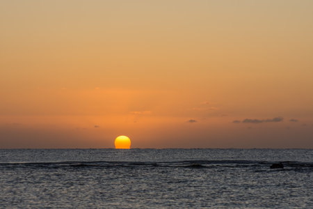 beautiful warm  sunrise with a distorted orange sun at the horizon from the red sea in egypt on vacationの写真素材