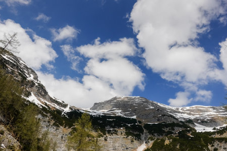 view to high snowy mountains with white clouds on the blue sky during hiking in the mountainsの写真素材