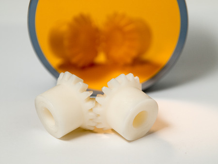 Bevel gear-wheels before a golden mirror isolated against a white background.の写真素材