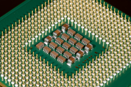 Microchips on the underside of a microprocessor, surrounded by the connector pins like a fence