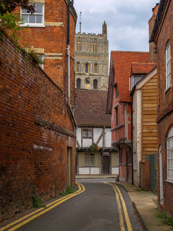 View of an alley with a tudoe house and the tower of Tewkesbury Abbey in Gloucestershire, Englandの写真素材
