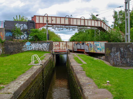 Stoke-on-Trent, Staffordshire, UK - MAY 17, 2015: Footbridge over a railwaybridge over a canal lock on the Trent and Mersey Canal. The walls of the bridges are decorated with graffiti.のeditorial素材