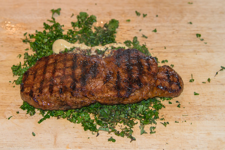 Steak on a plank in a bed of mustard and corianderの写真素材