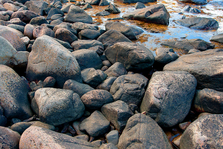 A closeup picture of black, grayish rocks making up a beach の写真素材
