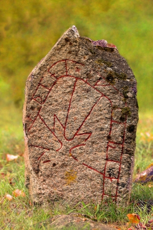 A closeup picture of swedish runestone against a vegetated, green background の写真素材