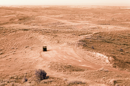 A solitary truck on a dirt road in a desert plain landscape の写真素材