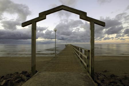A picture of a wooden bathing bridge with an arch over it, reaching quite far into the water の写真素材