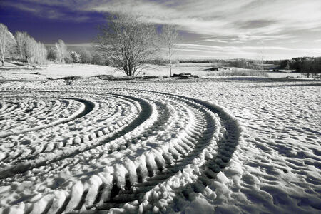 A picture of some tire tracks forming a pattern in the snow of a winter landscape の写真素材
