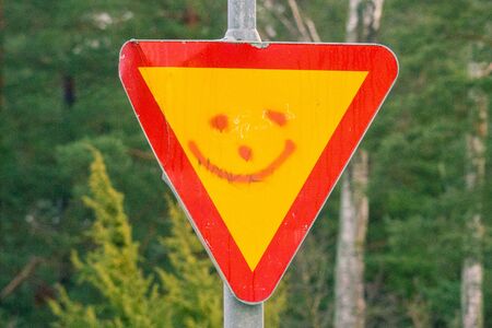 Smiley on a sign for Give priority to traffic on the main road aheadの写真素材