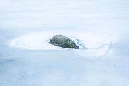 A rock on the frozen lake Valdermarenの写真素材