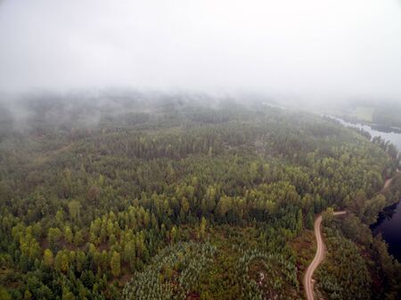 Cloudy day with a view of water surronded by forestの写真素材
