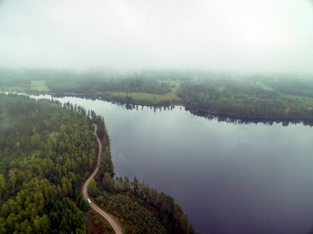 Cloudy day with a view of water surronded by forestの写真素材