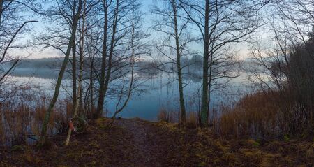 The shore line reflects in the surface of   the lake this calm dayの写真素材