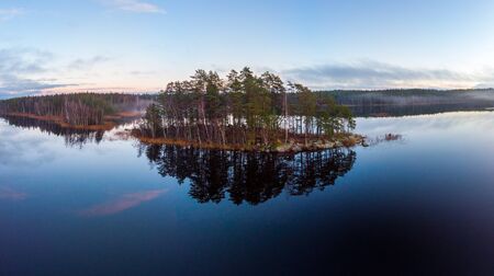The shore line reflects in the surface of   the lake this calm dayの写真素材