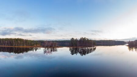 The shore line reflects in the surface of   the lake this calm dayの写真素材