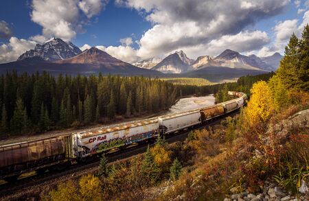 Freight train with many wagon driving in the scenic lanscape of Alberta, Canadaのeditorial素材