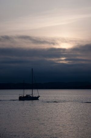 sailboat in dark sunsetの写真素材