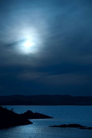 Scenic ocean view in the moonlight with hills in the backgroundの写真素材