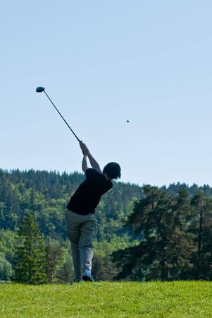 Male golfer driving in his finish with the ball in airの写真素材