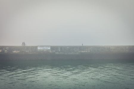 Fog on the pier of Les Sables d'Olonne (France) with two bicycles silhouettesの写真素材