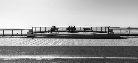 Sitting on benches facing the ocean in the embankment of Les Sables d'Olonne, Franceの写真素材