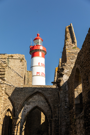 The Saint-Mathieu lighthouse behind the ruins of the abbey Saint-Mathieu de Fine-Terre in Plougonvelin (Finistere, France)の写真素材