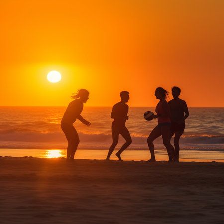Silhouette of a group of young people playing beach volleyball at sunsetの素材