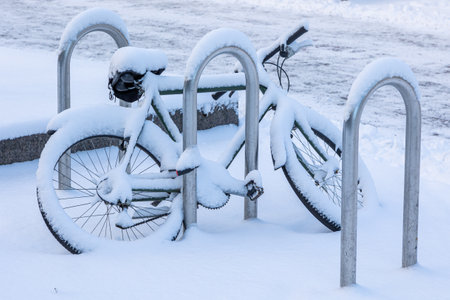 A bike left in a parking space with a thick layer of fresh snowの写真素材