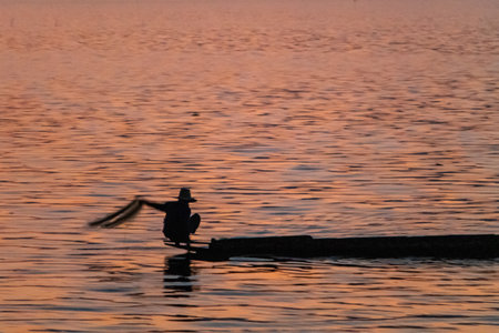 Sunset over lake Phayao with traditional fisherman in long tail boatの写真素材