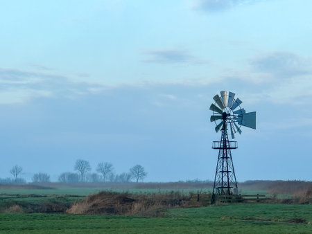 A windmill in the middle of a field with trees in the background