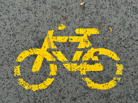 Yellow sign or symbol of a bike on a bicycle lane on black asphalt. High quality photoの写真素材