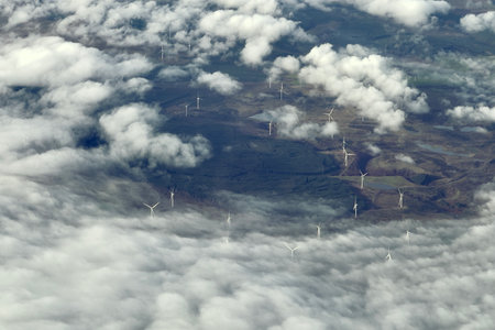 Windmills, windturbines above of the fog clouds in morning light
