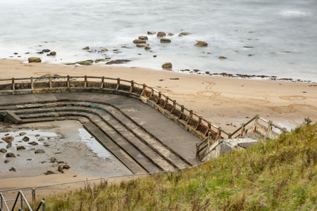Derelict forlorn ruin of outdoor swimming pool at sea water ocean of bygone glory days of long ago...