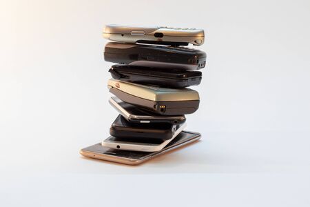 collection of old mobile phones stacked, piled in front of white background