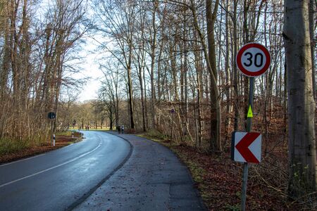 curve of a country road in the forest with speed limit sign, 30 kmhの写真素材