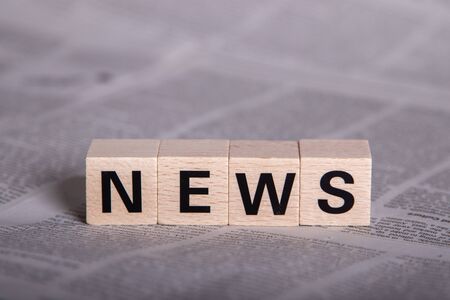 news, text on wooden cubes, newspaper as backgroundの写真素材