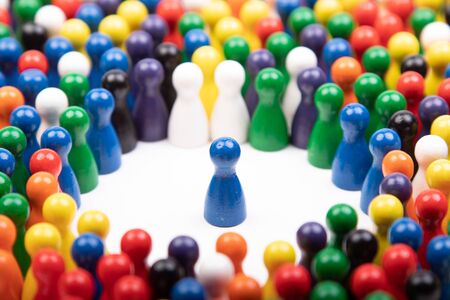 wooden blue figurine surrounded by a large group, standing for speaker or critical situationの写真素材