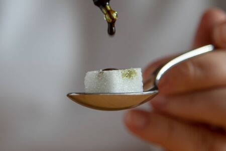 sugar cube on a tea spoon, medicine is added drop by drop using a pipette