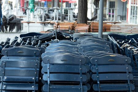 Folding chairs of an outside restaurant, folded up because the place is closed, other closed places in the backgroundの写真素材