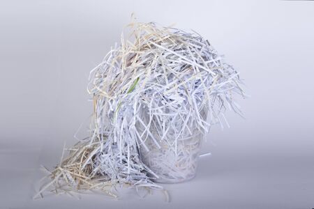 paper shredded with a shredder in a waste paper basket, white backgroundの写真素材