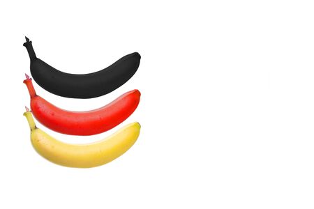 three bananas in yellow, red and black as german flag, white backgroundの写真素材