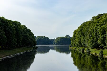 view on a lake with reflections of trees in the water, cloudy skyの写真素材