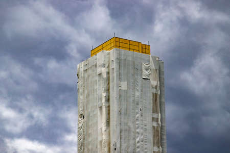 completely covered skyscraper for renovation work, cloud sky, outdoorsのeditorial素材