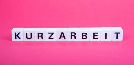 wooden blocks with german word for short time work, Kurzarbeit, red backgroundの写真素材